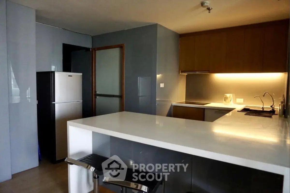 Modern kitchen with sleek design, featuring a breakfast bar and stainless steel appliances.
