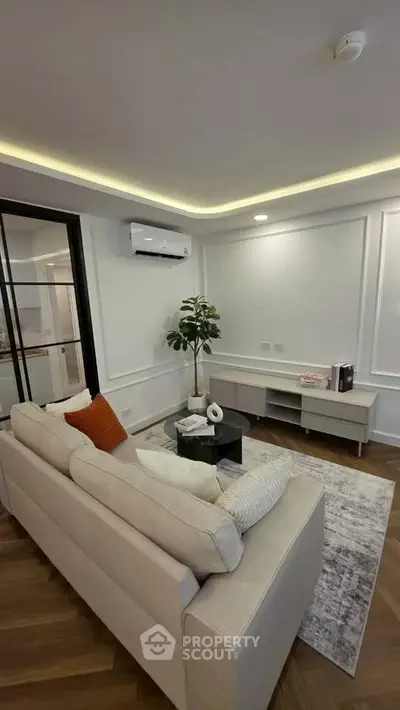 Modern living room with stylish decor and cozy seating area, featuring elegant lighting and wooden flooring.