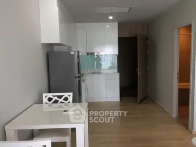 Modern kitchen with sleek white cabinets and dining area in a stylish apartment.