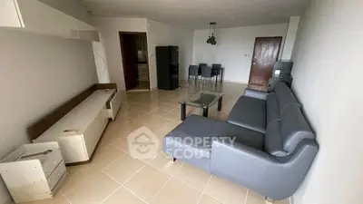 Spacious living room with modern gray sofa and dining area, ideal for comfortable living.