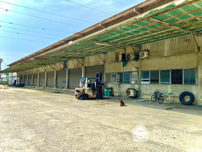 Spacious industrial warehouse exterior with loading docks and forklifts, ideal for logistics and storage.