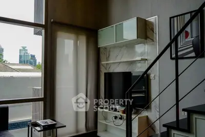 Modern living room with stylish decor and city view, featuring a sleek TV setup and contemporary staircase.