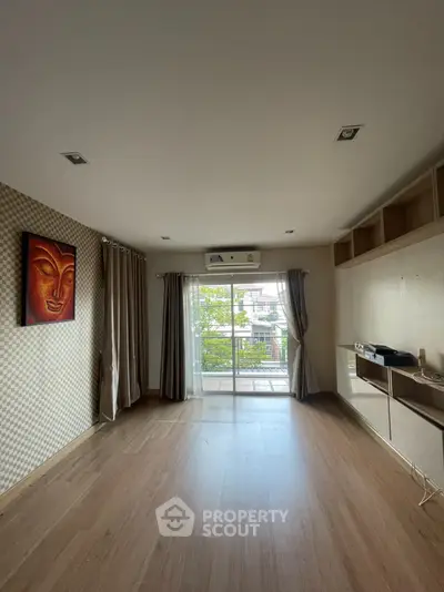Spacious living room with wooden flooring and balcony view