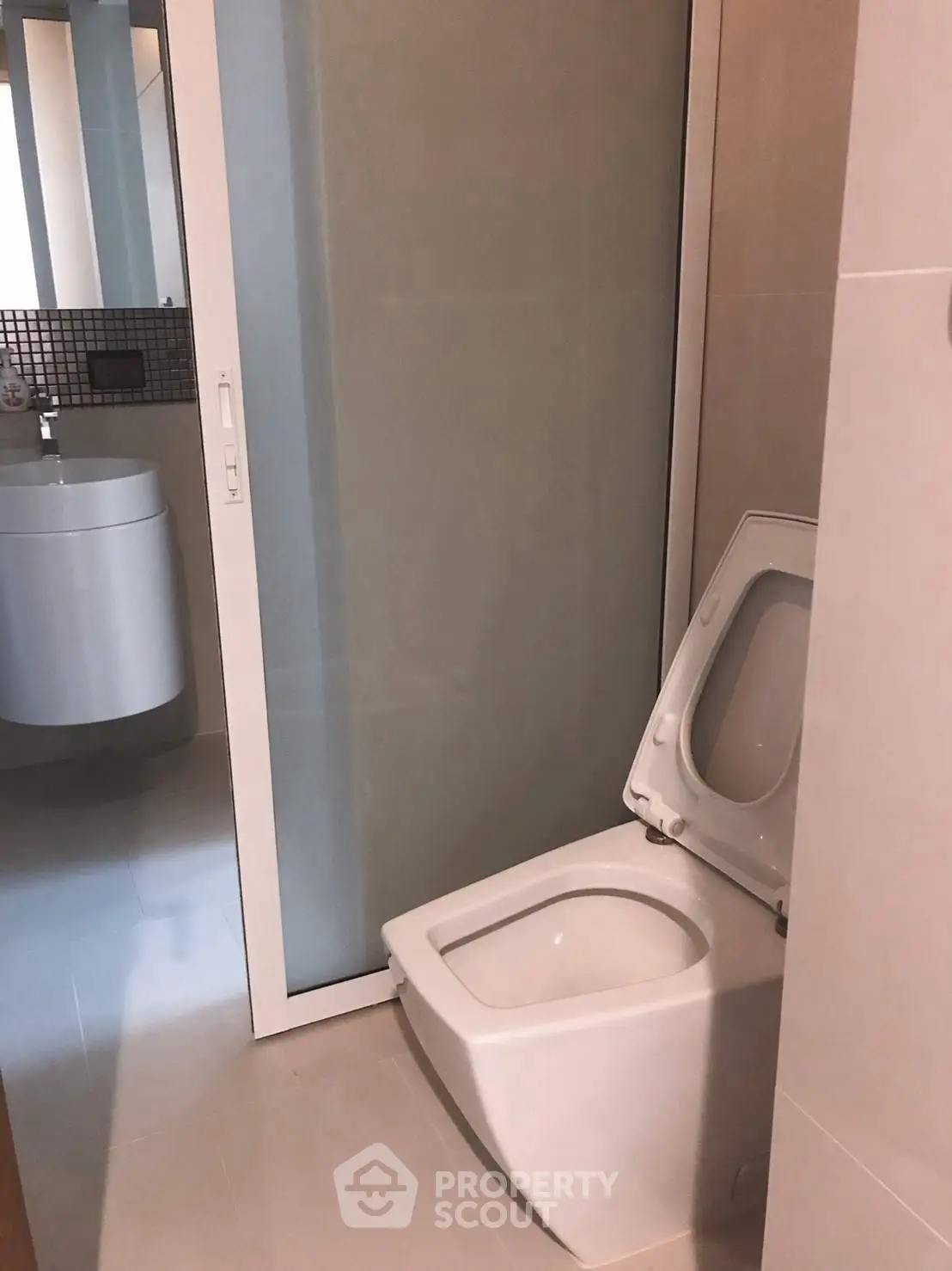 Modern bathroom with sleek toilet and glass partition for a contemporary look.