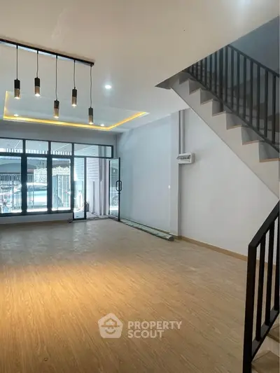 Spacious modern living room with elegant staircase and large windows