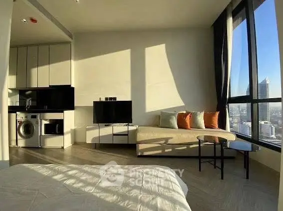 Modern living room with city view, featuring sleek furniture and built-in appliances.