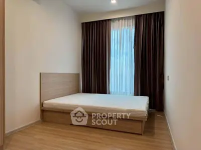 Modern minimalist bedroom with wooden flooring and large window with curtains.