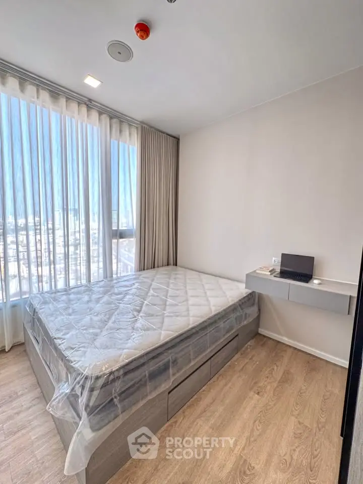 Modern bedroom with large window and natural light, featuring a minimalist design and wooden flooring.