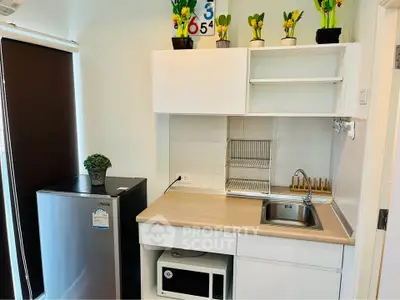 Modern compact kitchen with sleek white cabinets and stainless steel appliances, perfect for urban living.