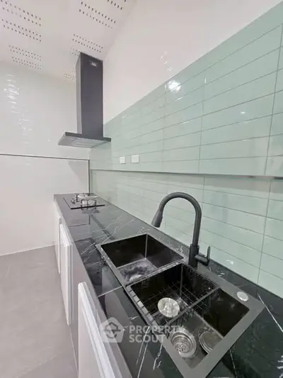 Modern kitchen with sleek black countertop and mint green backsplash