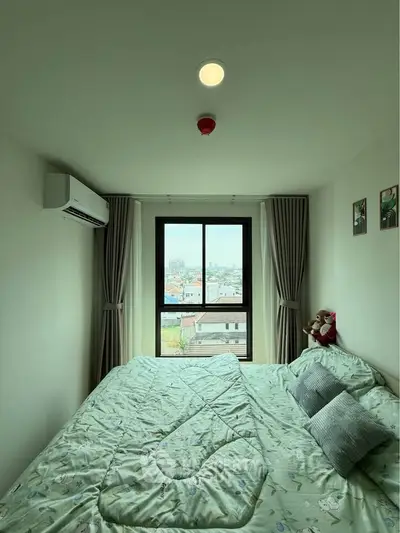 Cozy bedroom with city view, featuring a large window and air conditioning.