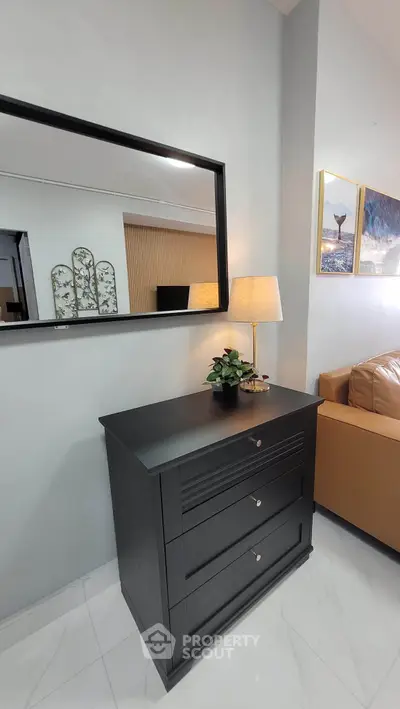 Stylish living room corner with elegant black dresser and mirror, cozy sofa, and chic decor.