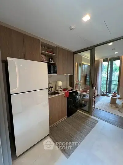Modern kitchen with sleek appliances and open layout leading to a bright dining area with balcony view.