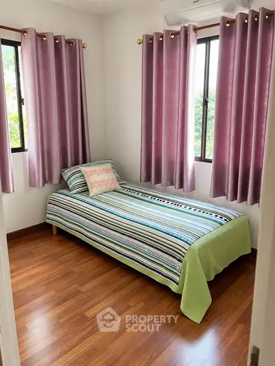 Cozy bedroom with single bed and vibrant curtains, perfect for a peaceful retreat.