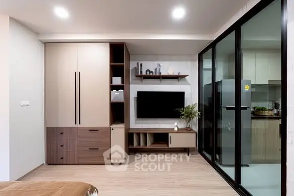 Modern living room with sleek furniture and glass partition to kitchen