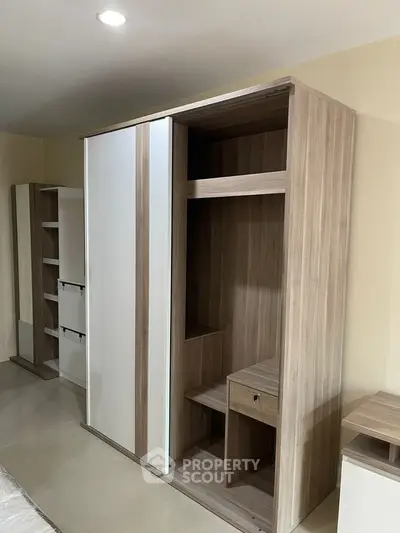 Modern bedroom with sleek wooden wardrobe and ample storage space.