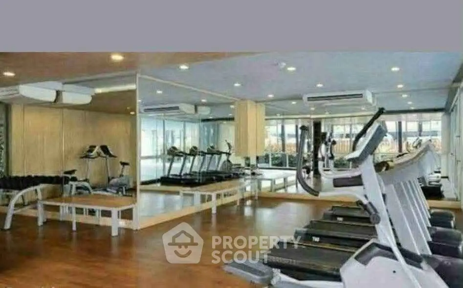 Spacious modern gym with state-of-the-art equipment and mirrored walls in luxury building.