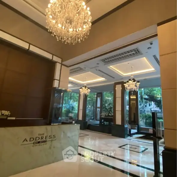 Luxurious building entrance with elegant chandeliers and marble flooring.