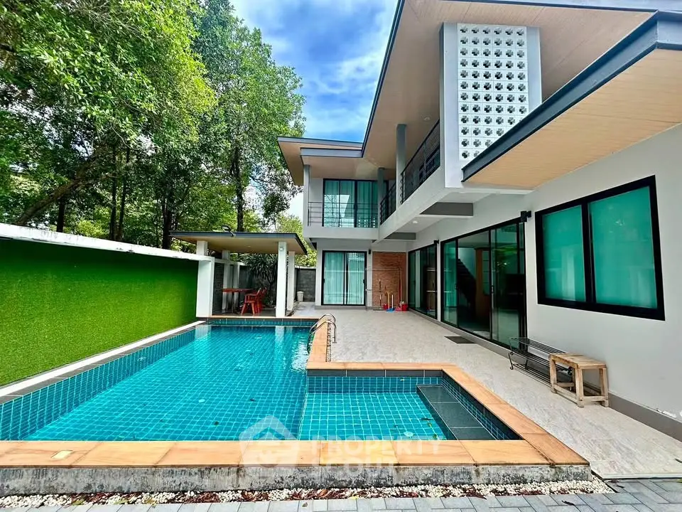 Modern luxury home with private pool and spacious outdoor area, surrounded by lush greenery.