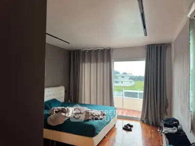 Spacious bedroom with large window and balcony view, featuring modern decor and natural light.