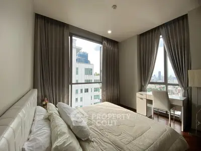 Modern bedroom with city view, featuring elegant decor and natural light through large windows.