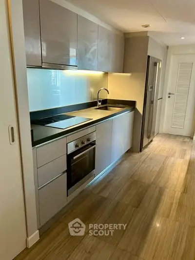 Modern kitchen with sleek cabinetry and built-in oven in a stylish apartment.