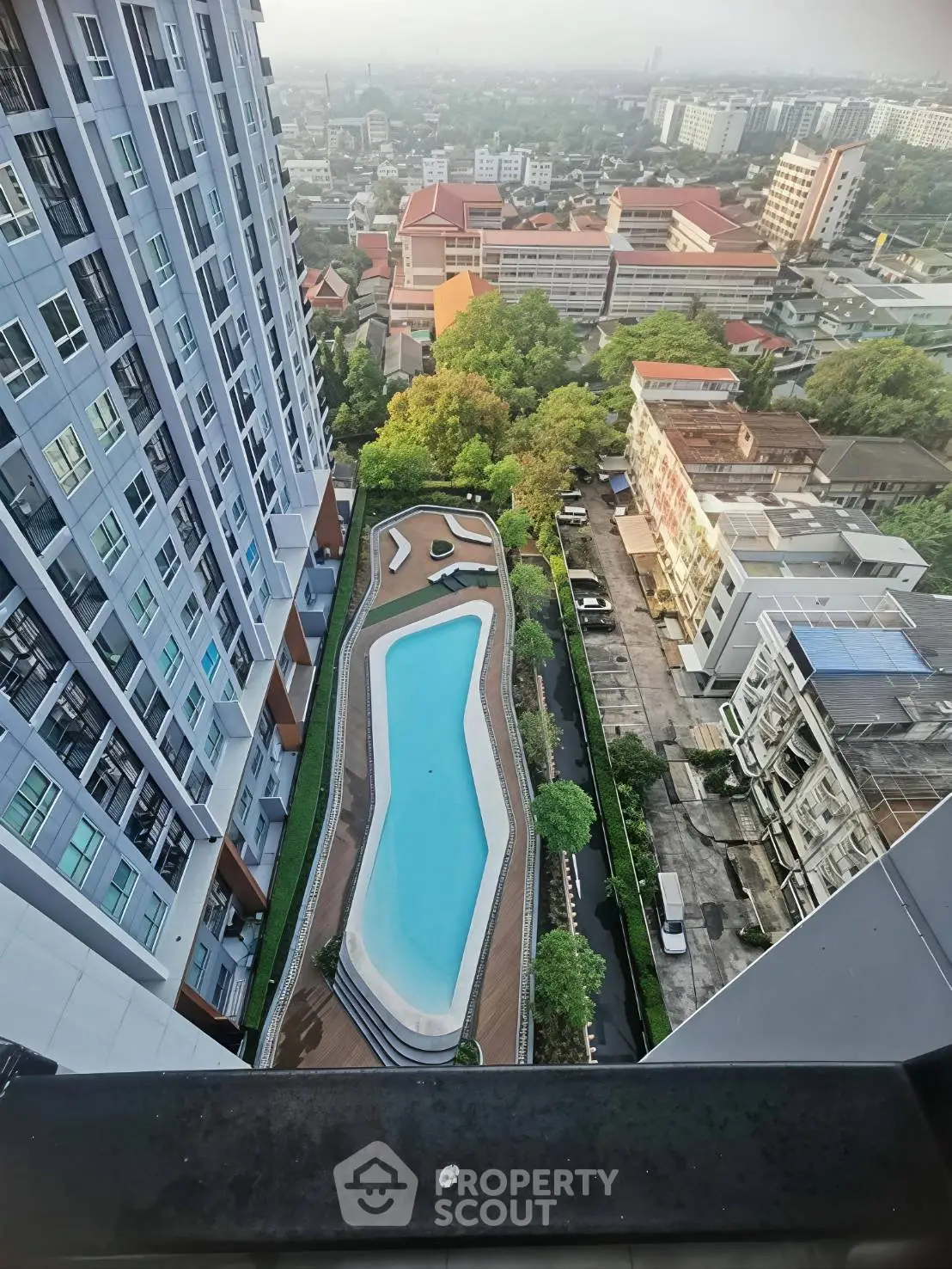 Stunning aerial view of modern high-rise building with luxurious swimming pool and cityscape backdrop.