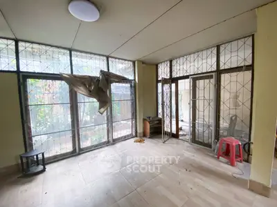 Spacious room with large windows and garden view, potential for renovation.