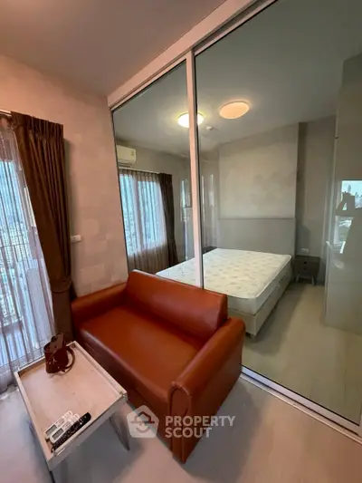 Modern apartment interior with glass partition separating living room and bedroom, featuring stylish furniture.