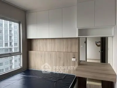 Modern bedroom with built-in storage and large window in urban apartment