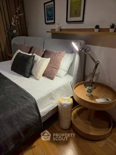 Cozy bedroom with stylish decor, featuring a plush bed, elegant lighting, and wooden flooring for a warm ambiance.