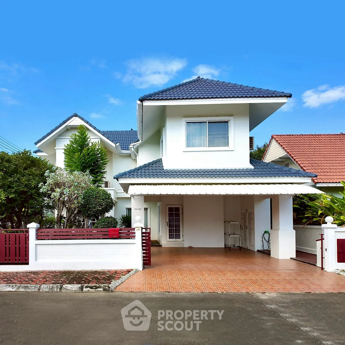 Charming two-story house with tiled roof and spacious driveway in a serene neighborhood.
