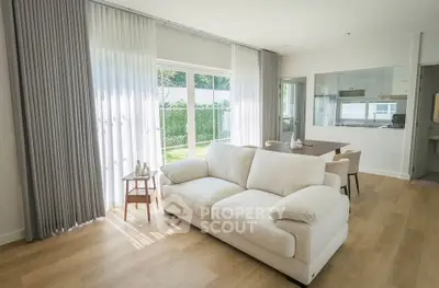 Bright and spacious living room with modern decor and large windows overlooking a lush garden.