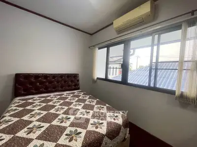 Cozy bedroom with quilted bedspread and large window offering natural light.