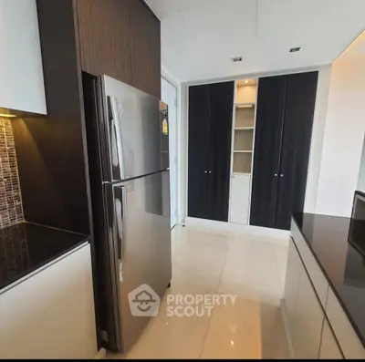 Modern kitchen with sleek cabinetry and stainless steel refrigerator in a contemporary apartment.