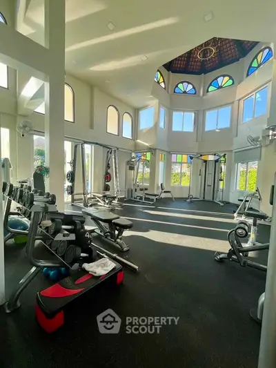 Luxurious gym with high ceilings and modern equipment in a sunlit room