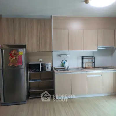 Modern kitchen with sleek wooden cabinets and stainless steel appliances in a stylish apartment.