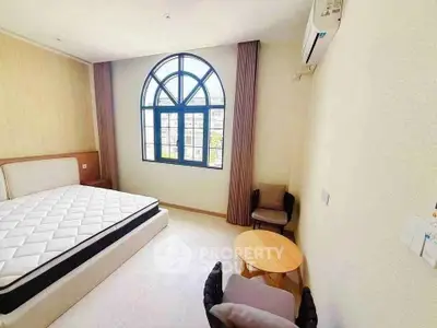 Bright bedroom with large arched window and modern furnishings