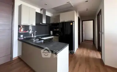 Modern kitchen with sleek design and open layout, featuring black countertops and wooden flooring.
