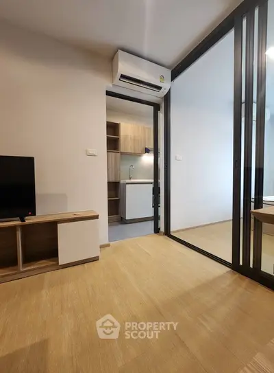 Modern apartment interior with sliding glass doors and compact kitchen.