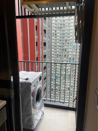 Modern high-rise apartment balcony with washing machine and city view.