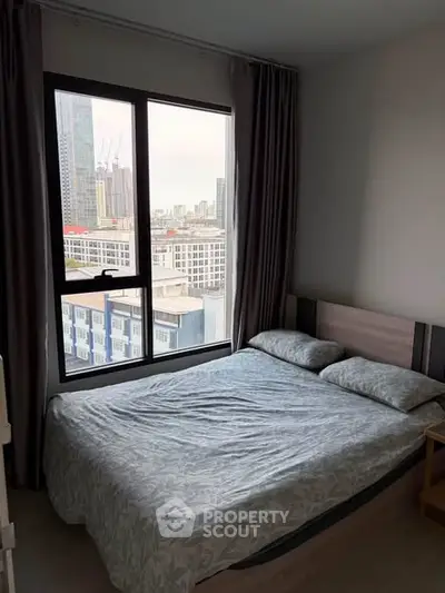 Cozy bedroom with city view, featuring a comfortable bed and large window for natural light.