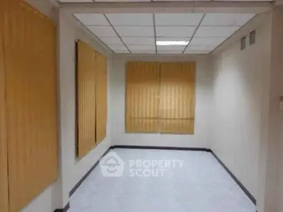 Spacious empty room with large windows and blinds, ideal for customization.
