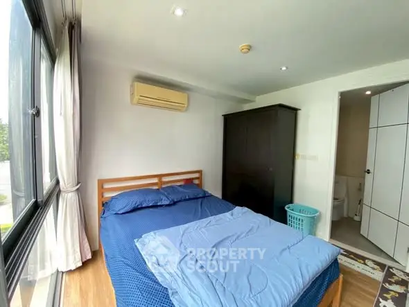 Cozy bedroom with large window and modern furnishings in a bright apartment.