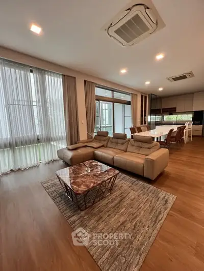 Spacious modern living room with elegant furniture and large windows offering natural light.