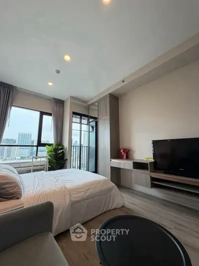 Modern bedroom with city view, featuring sleek furniture and large windows for natural light.