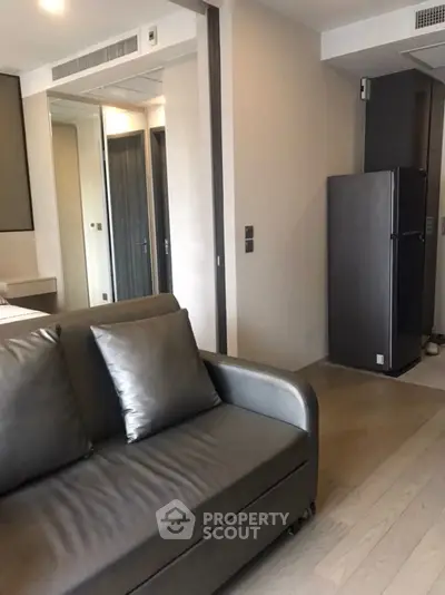 Modern living room with sleek sofa and compact kitchen area in stylish apartment.