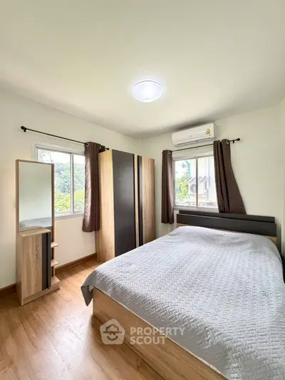 Cozy bedroom with modern furnishings and large windows offering natural light and scenic views.