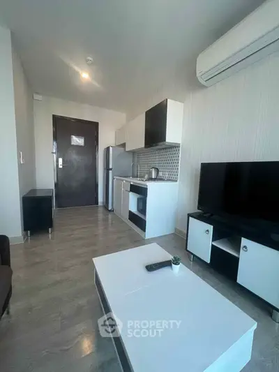 Modern living room with sleek furniture and open kitchen layout, featuring air conditioning and stylish decor.