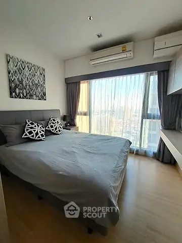 Modern bedroom with large window and stylish decor in a high-rise apartment.